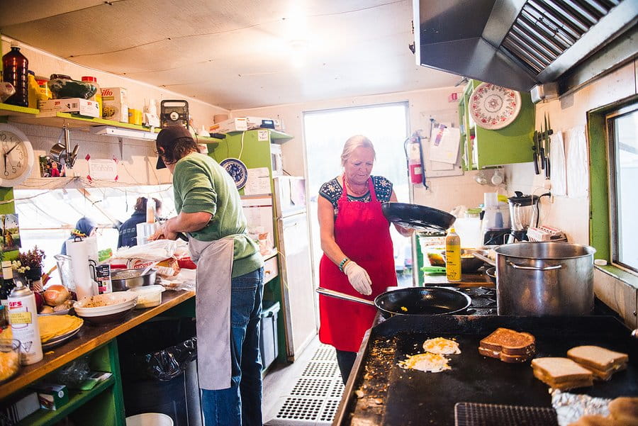 Two cook staff prepare breakfast for the camp in the kitchen