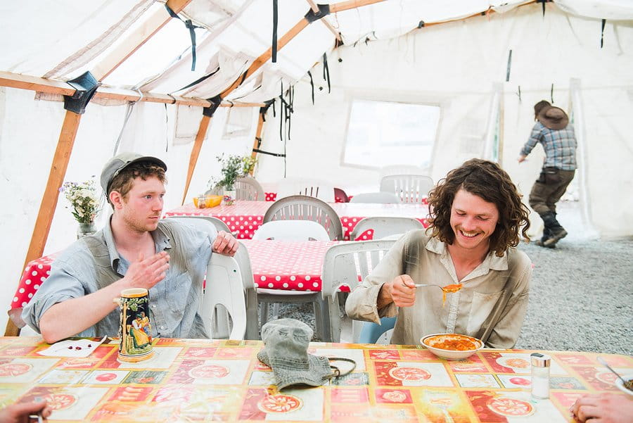 Two young tree planter men having food together in the mess tent