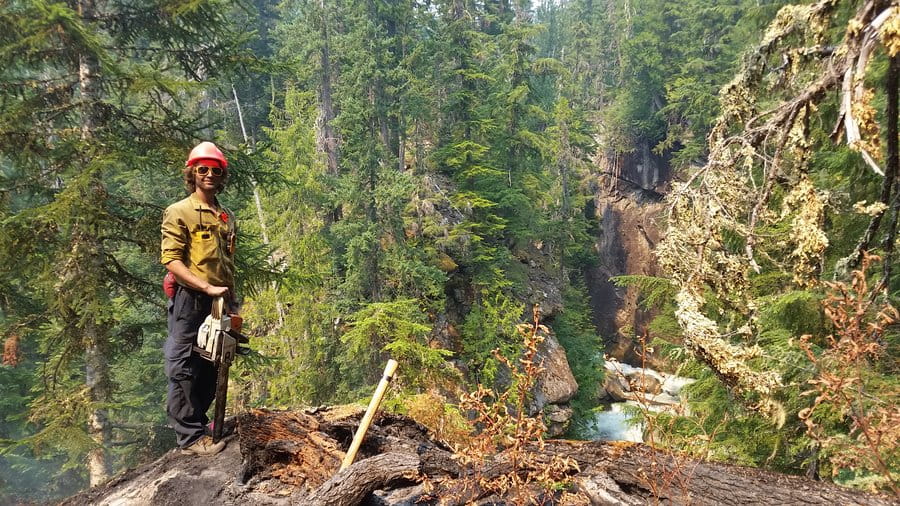 A Wildland fire fighter power saw operator stands on lookout